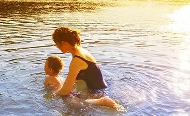 Mother helping child float in a lake