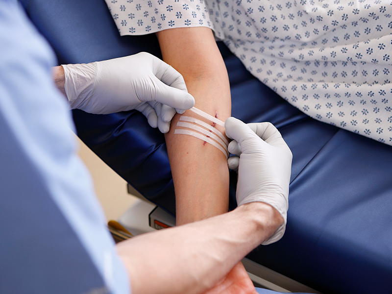 Medical professional applying tape to a cut on a patient's arm