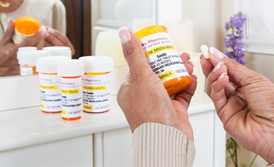 Woman holding prescription bottle and pill