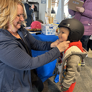 Woman fastening helmet on young child