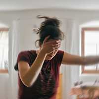 Woman with hand on head, blurred background indicates movement