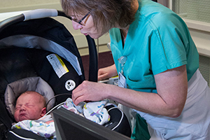 Woman with newborn baby in a carseat