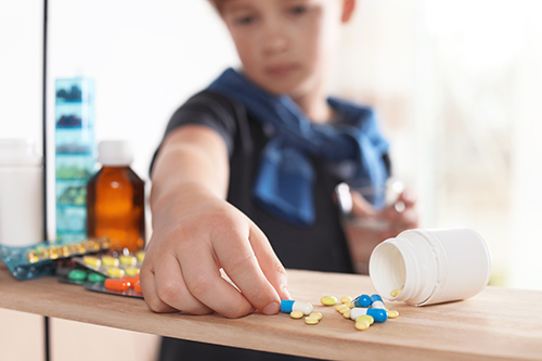 Child reaching for pills on shelf