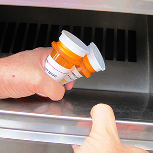 Hands dropping pill bottles into MedSafe bin
