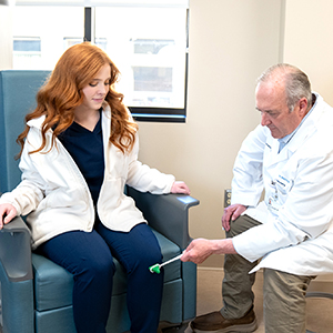 Neurosurgeon John Campbell testing reflexes of patient in the office