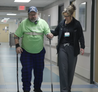 Man walking assisted by therapist