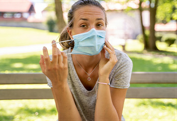 Woman outdoors taking off mask