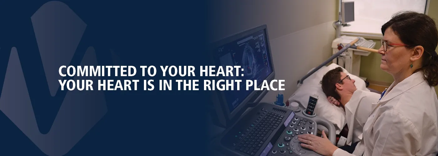 Physician at bedside of patient. Committed to Your Heart.