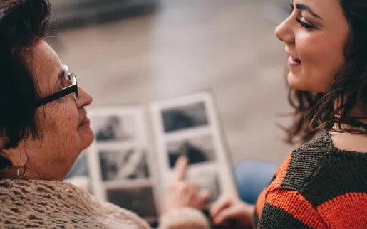 Two women looking at a photo album and talking
